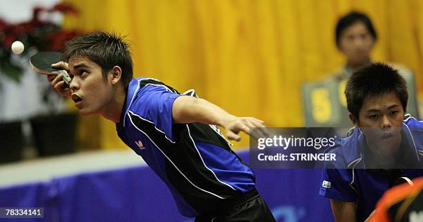 Malaysian table tennis player Ibahim Muhd Shakirin eyes the ball as his partner Chai Kian Beng gets ready during the men's doubles semi-final of the...