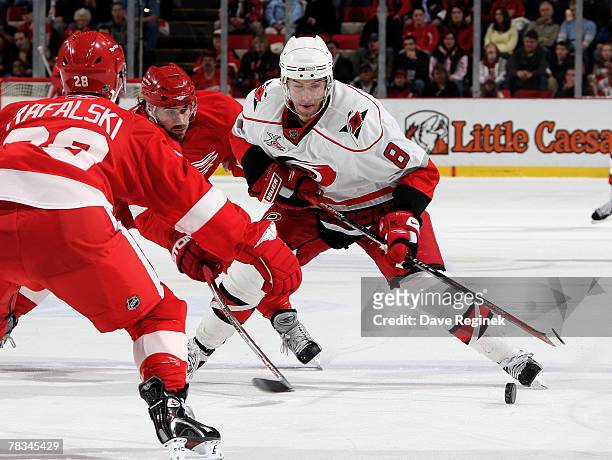 Matt Cullen of the Carolina Hurricanes tries to skate by the defence of Brian Rafalski and Henrik Zetterberg of the Detroit Red Wings on December 9,...