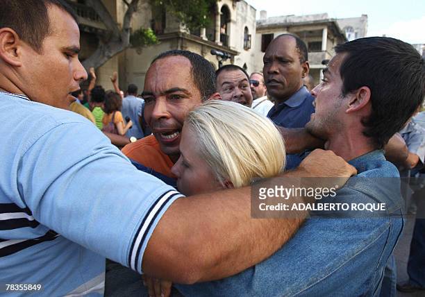 Anti-Castro leader Darsy Ferrer embraces another activist as they are surrounded by Pro-Castro Cubans shouting slogans during their protest in the...