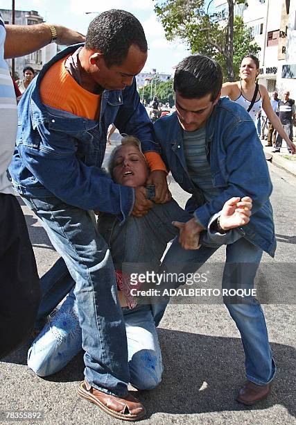 An exhausted Anti-Castro activist is helped by Cuban opponent and leader Darsy Ferrer and another activist during their protest in the streets of...