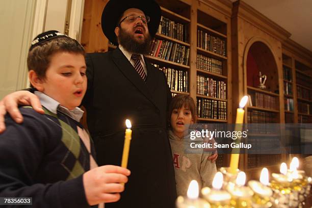 Orthodox Jewish Rabbi Yehuda Teichtal and two of his children, David and Chana sing after lighting a menorah at their home on the second to last...