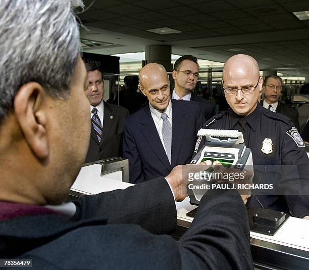 Department of Homeland Security Officer Brian Pittack stands at his station as the Secretary of DHS Michael Chertoff watches a passenger from South...