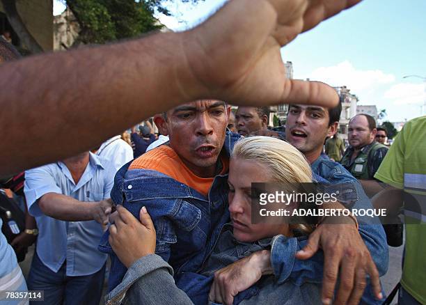Anti-Castro leader Darsy Ferrer embraces another activist as they are surrounded by Pro-Castro Cuban people shouting slogans during their protest in...