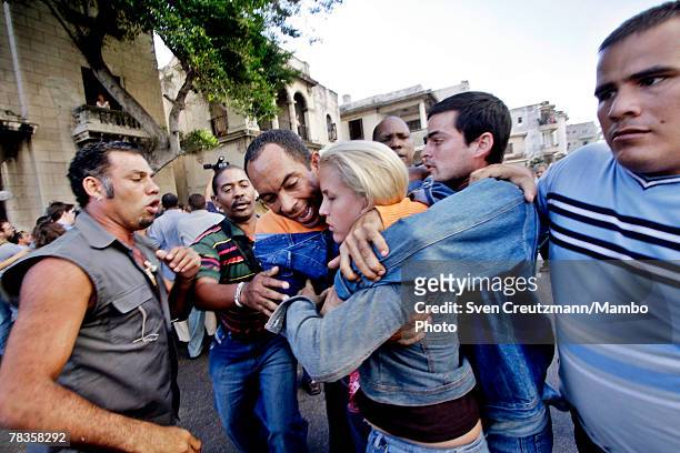 Cuban dissident leader Darsy Ferrer hugs a fellow actiivist as they are surrounded by government supporters during a march in commemoration of the...