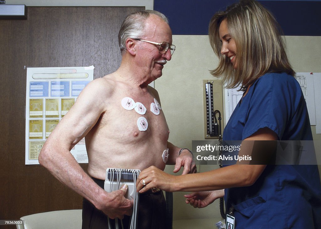 Nurse checking medical equipment on man