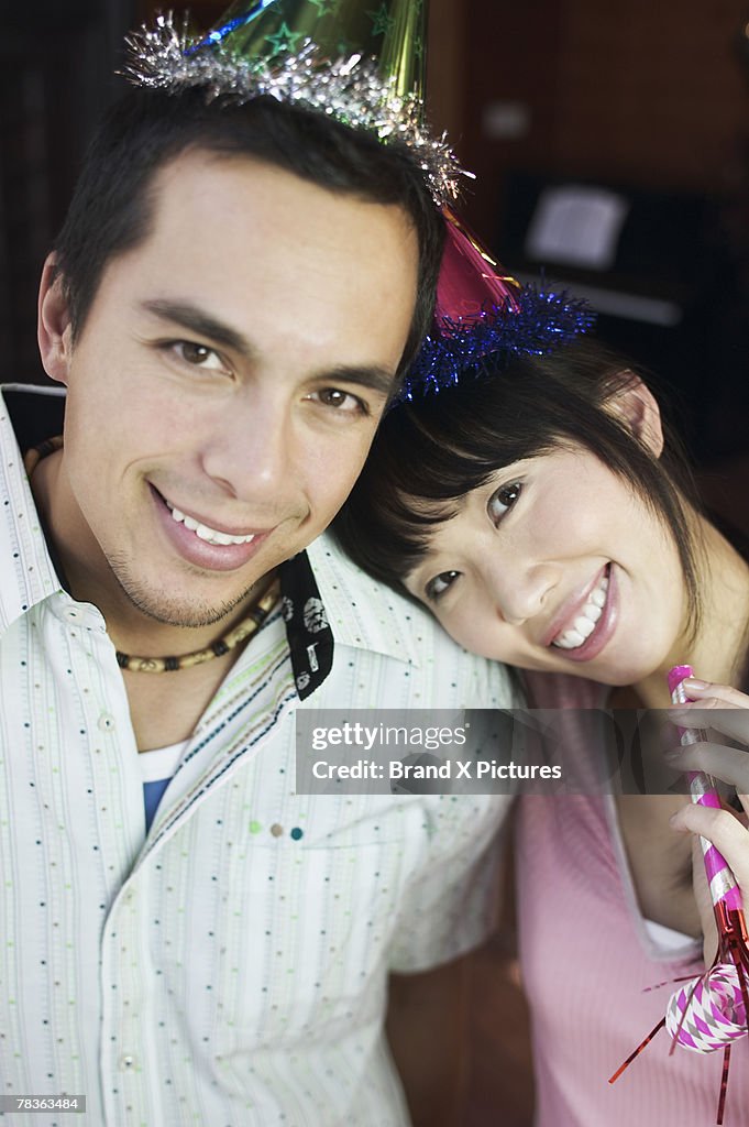 Smiling couple with party hats and noisemaker