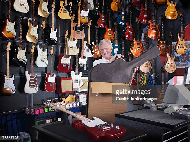 man lifting guitar case out of box - music shop stock pictures, royalty-free photos & images