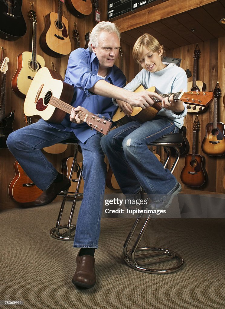 Man giving boy guitar lesson in music store