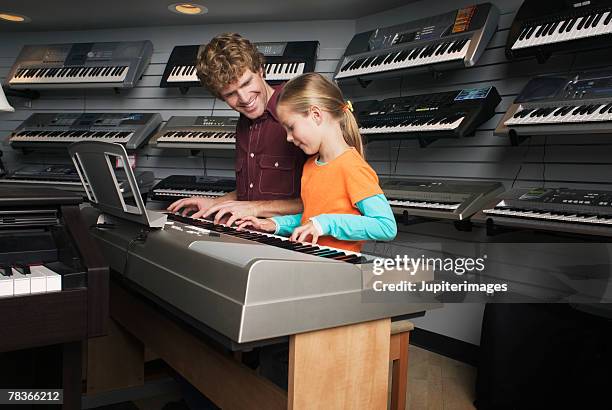 man and girl playing keyboard together in music store - music shop stock pictures, royalty-free photos & images