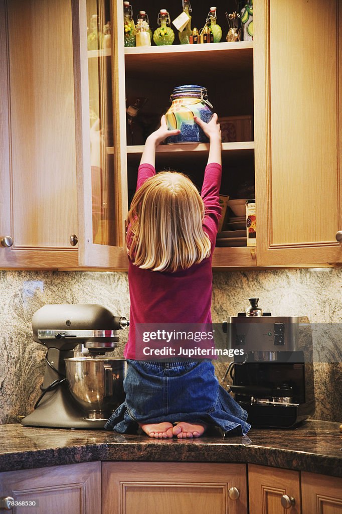 Girl taking treats out of cabinet