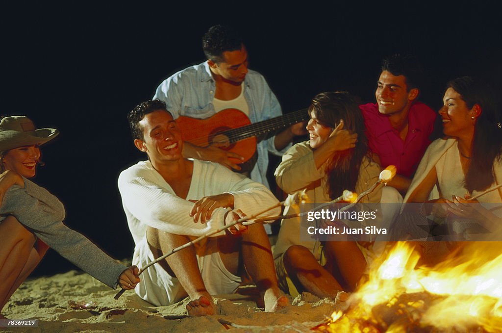 Friends sitting around beach bonfire