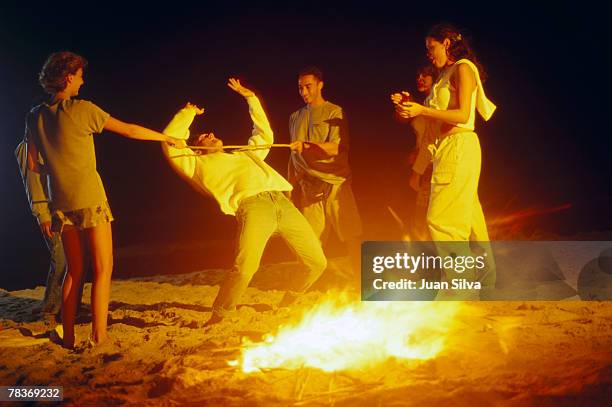 friends limboing on beach at night - limbo stock-fotos und bilder