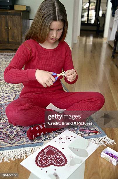 girl making valentine card - child cutting card stock-fotos und bilder