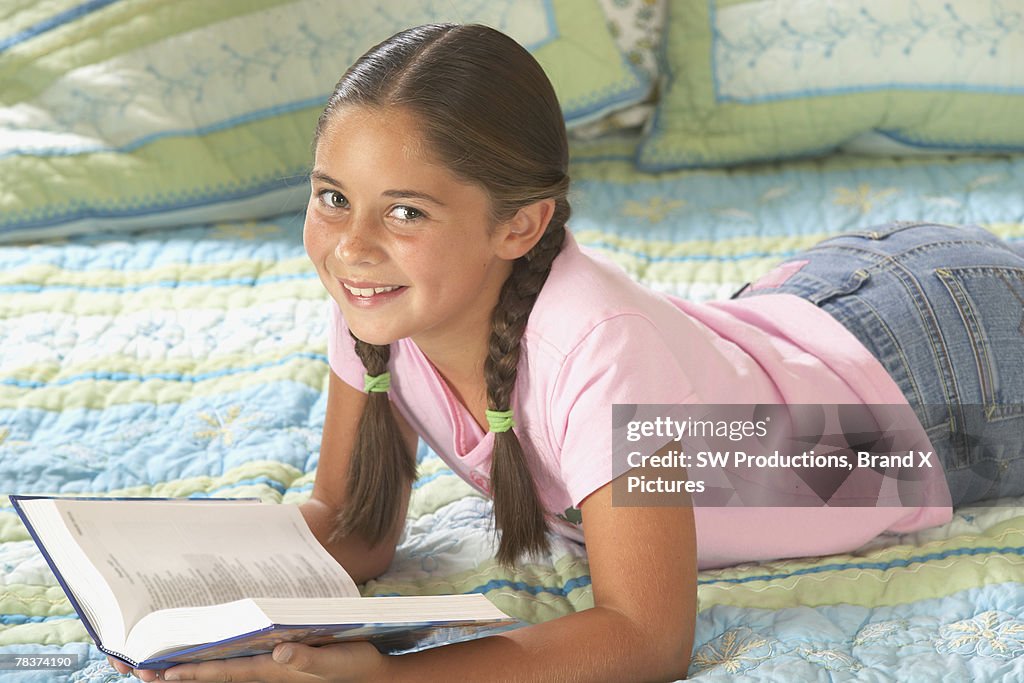 Girl lying on bed reading book