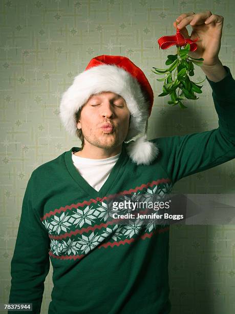 man holding mistletoe - studio kiss stock-fotos und bilder