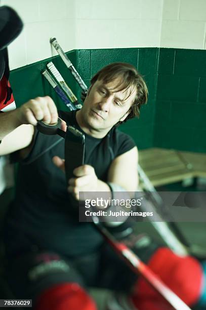ice hockey player taping hockey stick - ijshockeystick stockfoto's en -beelden