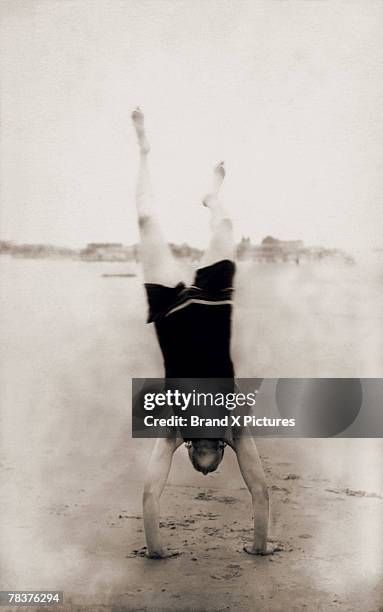 man doing handstand on beach - handstand beach photos et images de collection