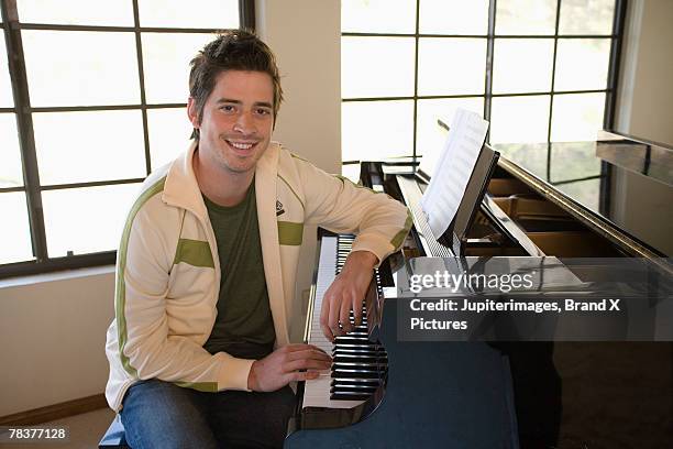 mid-adult man seated at piano - pianist stock pictures, royalty-free photos & images