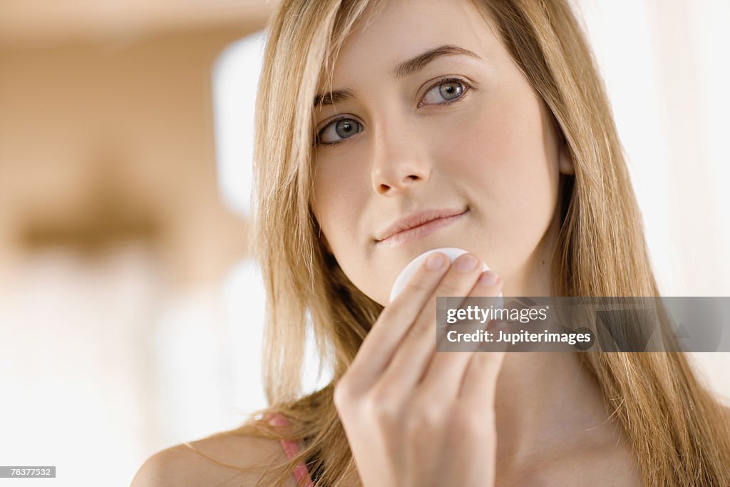 Teenage girl wiping chin with cosmetic pad