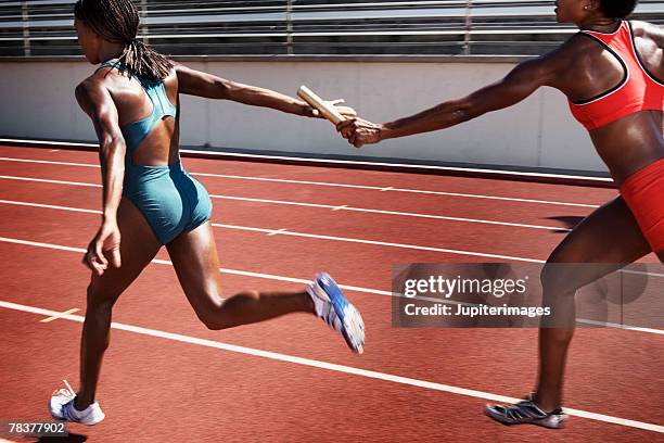 women passing baton to each other during race - passes photos et images de collection