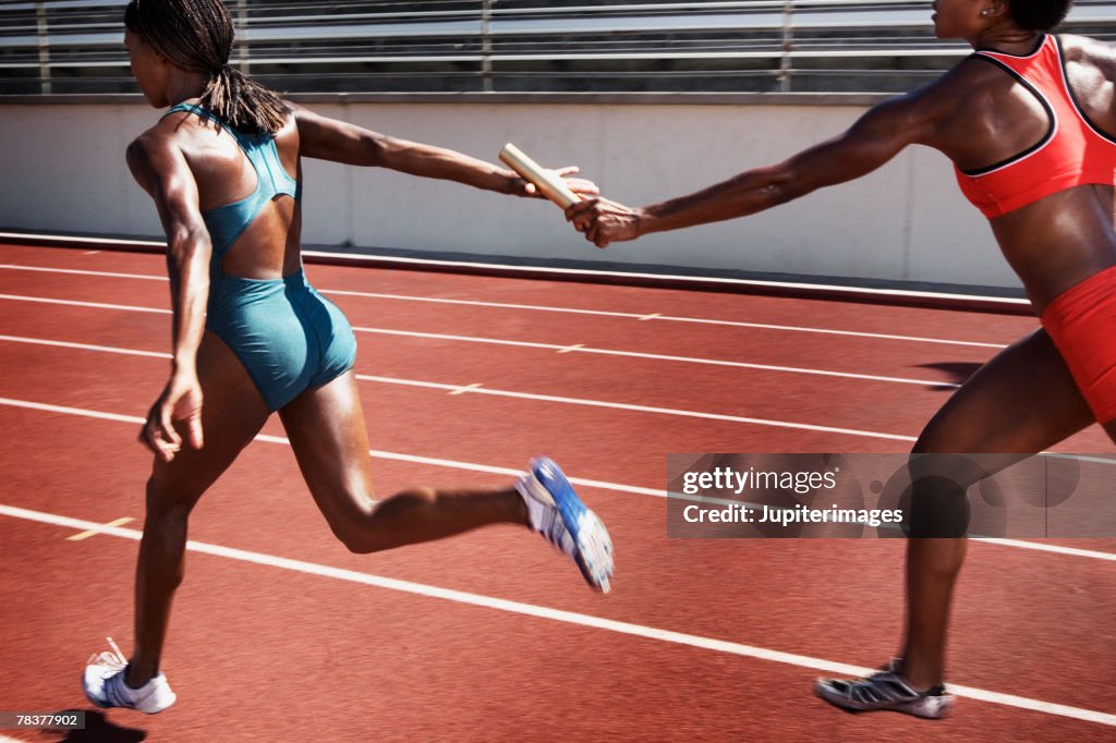 Women passing baton to each other during race