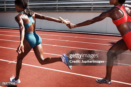 Women passing baton to each other during race Women passing baton to each other during race