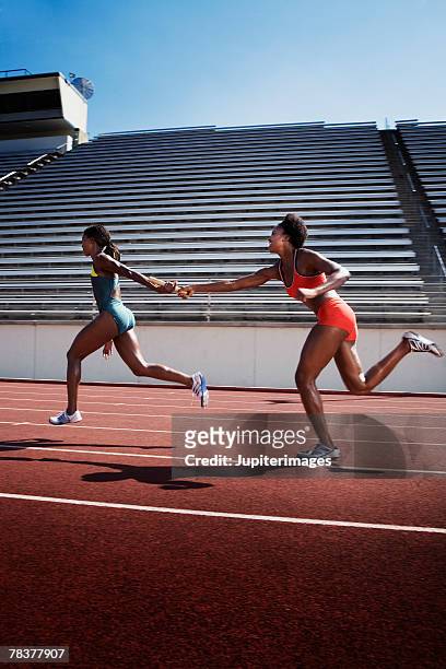 women passing baton to each other during race - staffel stock-fotos und bilder