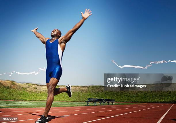 runner crossing finish line - athletics stock pictures, royalty-free photos & images