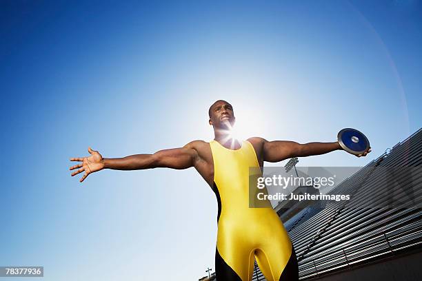 man standing on athletic track holding a discus - discus stock-fotos und bilder