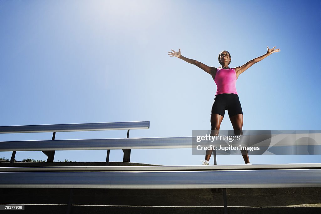 Athletic woman standing at the top of bleachers