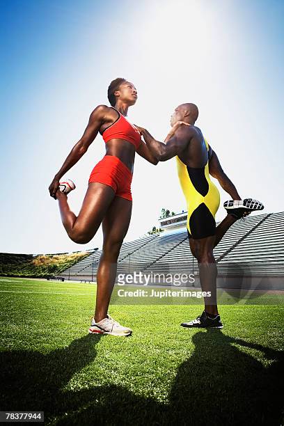 athletic man and athletic woman stretching on field - repetição evento esportivo imagens e fotografias de stock