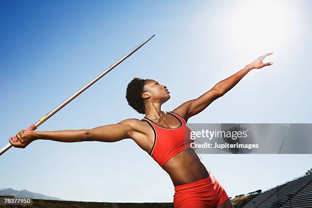 athletic woman throwing a javelin - speerwurf stock-fotos und bilder