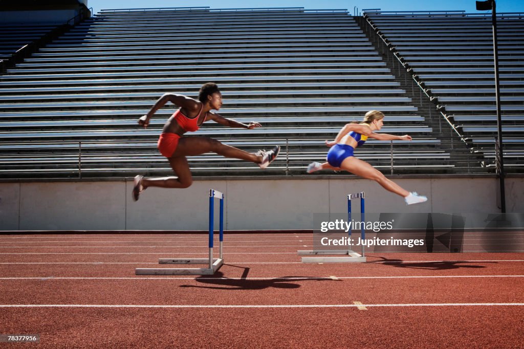 Women jumping over hurdles