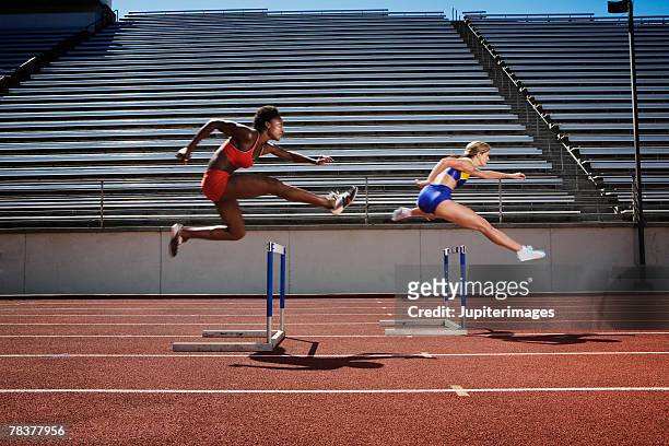women jumping over hurdles - leichtathletik stock-fotos und bilder