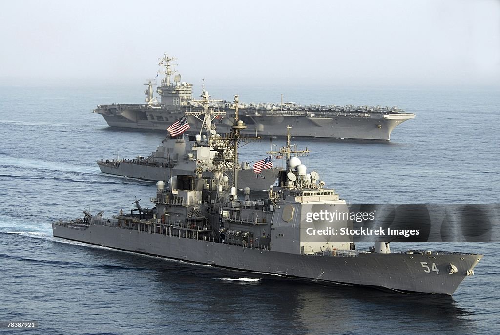 Military ships transit through open water.