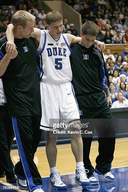 Martynas Pocius of the Duke Blue Devils is helped off court during the game against the Eastern Kentucky Colonels at Cameron Indoor Stadium on...