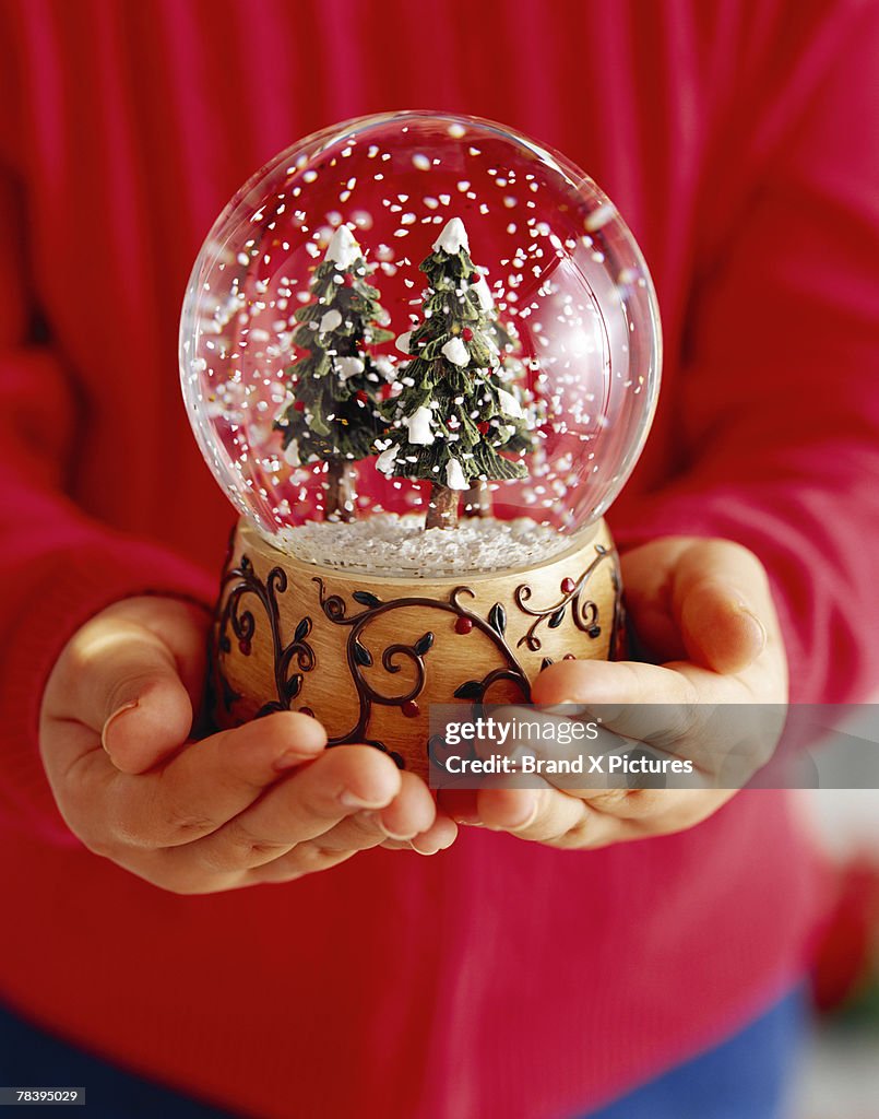 Child's hands holding snow globe