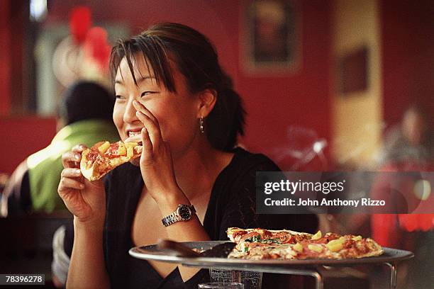 woman eating pizza in restaurant - hawaiian pizza stock pictures, royalty-free photos & images