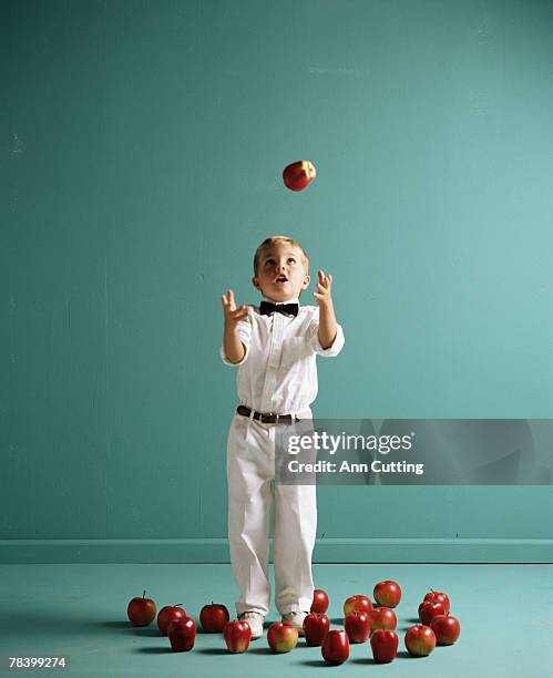 boy in formal wear trying to juggle apples - juggling stock pictures, royalty-free photos & images