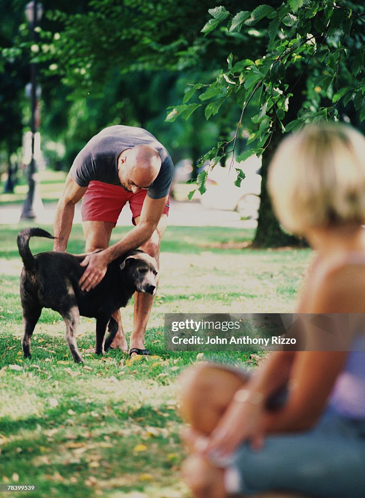 Couple petting dog in dog park