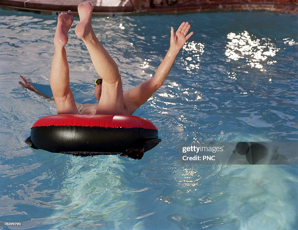Man jumping into pool in innertube