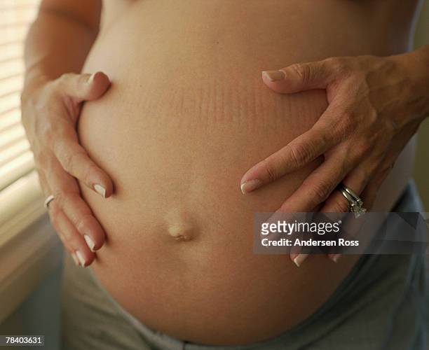 woman holding pregnant belly - belly ring photos et images de collection
