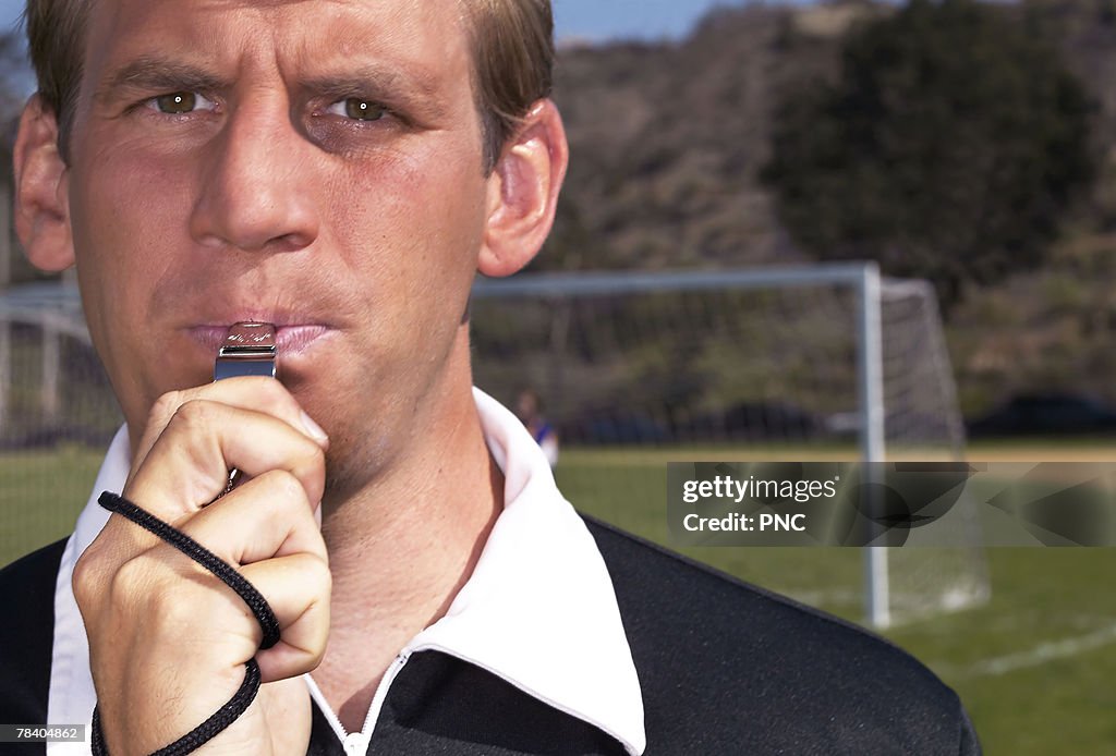 Soccer referee blowing whistle