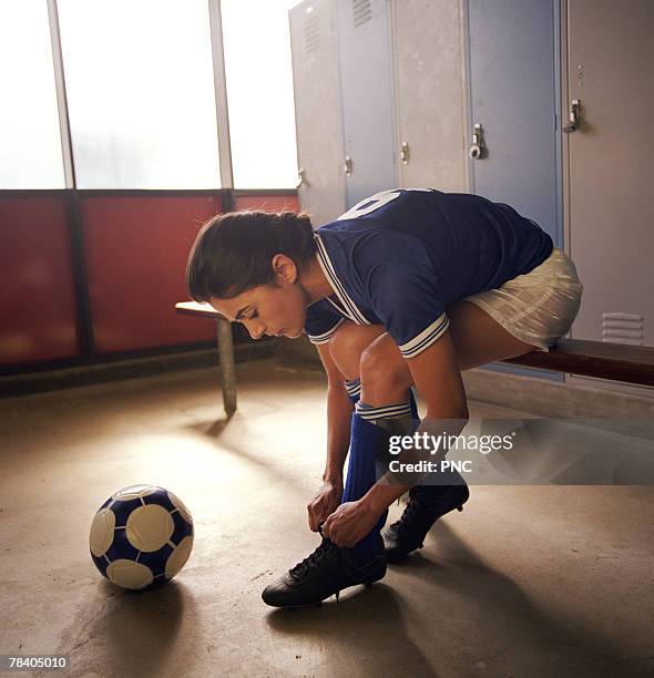 soccer player tying cleats in locker room - studded footwear stock pictures, royalty-free photos & images