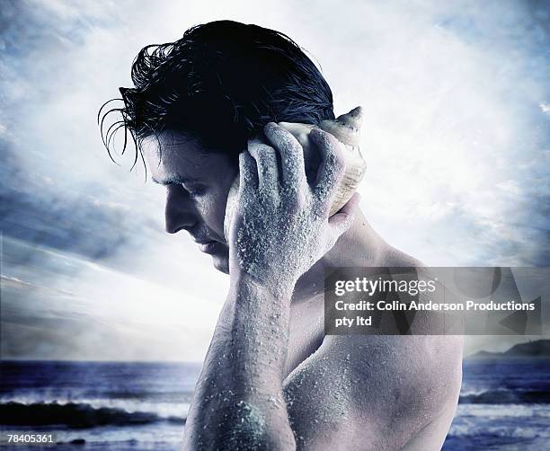 man listening to with seashell - life si a beach stock pictures, royalty-free photos & images