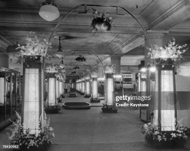 The illuminated floral aisle of Selfridges flagship store on London's Oxford Street, 1934.