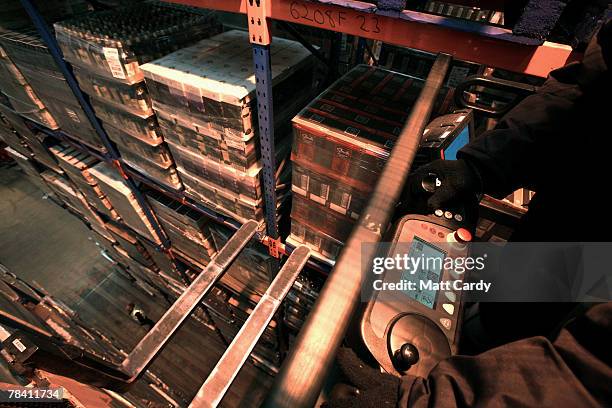 Fork lift crane driver Steve Stiley reaches for a pallet on the top of a rack as Howard Cobb watches from below at the giant distribution centre in...