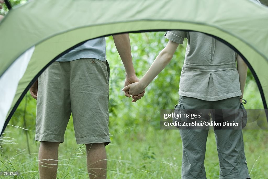 Young couple holding hands, seen through tent