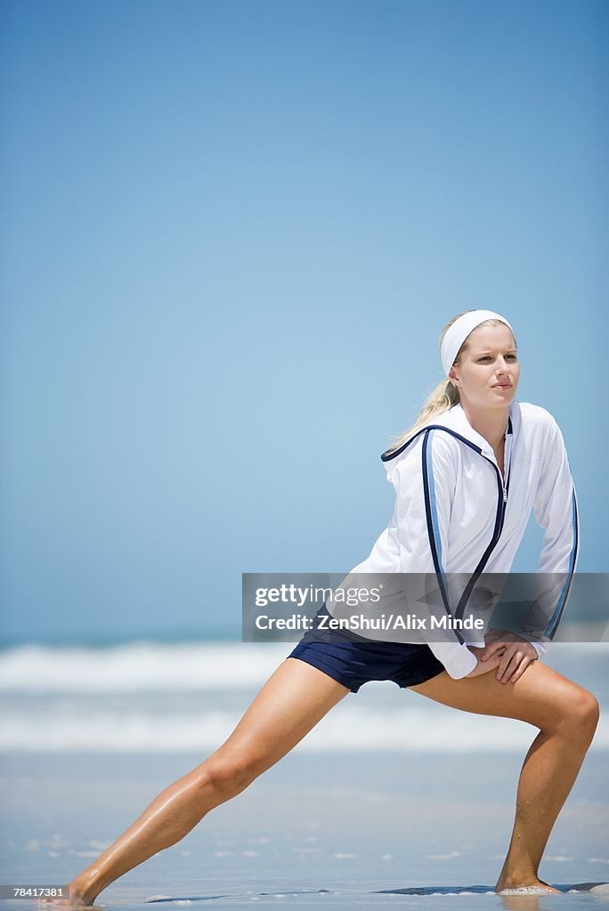 Young woman on beach, stretching