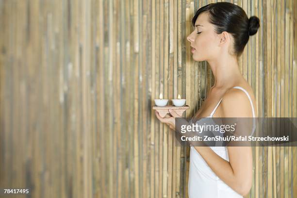 young woman holding tray of candles, side view - キャミソール ストックフォトと画像